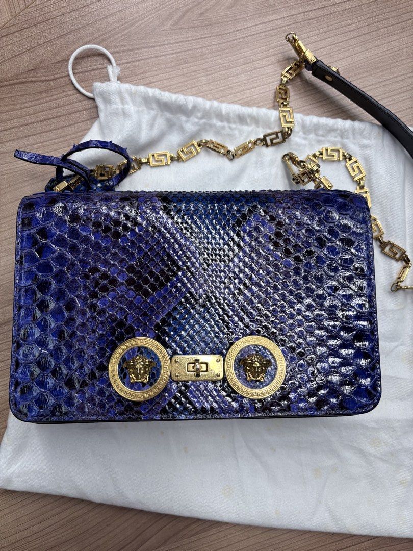 Versace Tribute ( Medium Python Leather) （分類：手袋及銀包）位於 Hong Kong。 由 just.wanna.sell.store 提交（商品編號 1467746909，圖片 1）。簡介： Versace Tribute ( Medium Python Leather) 設計與特色： ✨天然蟒蛇皮打造，保留材質獨特立體質感&豐富鱗片紋理。 ✨精湛工藝染色，呈現神秘奢華的藍紫漸變色調，不同光線下折射出光澤 ✨翻蓋正面飾有圓形金屬扣，中央鑲嵌品牌標誌性的希臘神話「美杜莎頭像」圖案 ✨肩帶採用拼接設計，由質感厚實的金色金屬鏈條構成，並融入了幾何風格的希臘迴紋（Greek Key）圖案 ✨袋身背面設有外置插袋，無需打開翻蓋即可快速收納卡片。 尺寸： 寬：20 - 22 cm 高：13 - 14 cm 深：4 - 5 cm 搭配建議： 精緻的同色系（Monochromatic） 黑色穿搭，與手袋形成對比 奢華小黑裙（適合正式場合及晚間活動） Desig