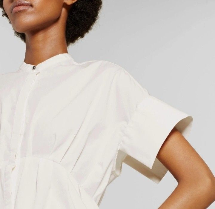 Victoria Beckham Button-Down Blouse (Category: Blouses) located in Cabanatuan. Submitted by miss.maia (Listing ID 1467803831, Image 3). Description: Button-Down Blouse. Design Features: This crisp white 100% cotton poplin shirt features a distinctive band/mandarin collar, a button-front placket, and mid-length short sleeves. The defining element is the cinched, elasticized gathered waist that flows into a flared peplum-style hemline with a subtle