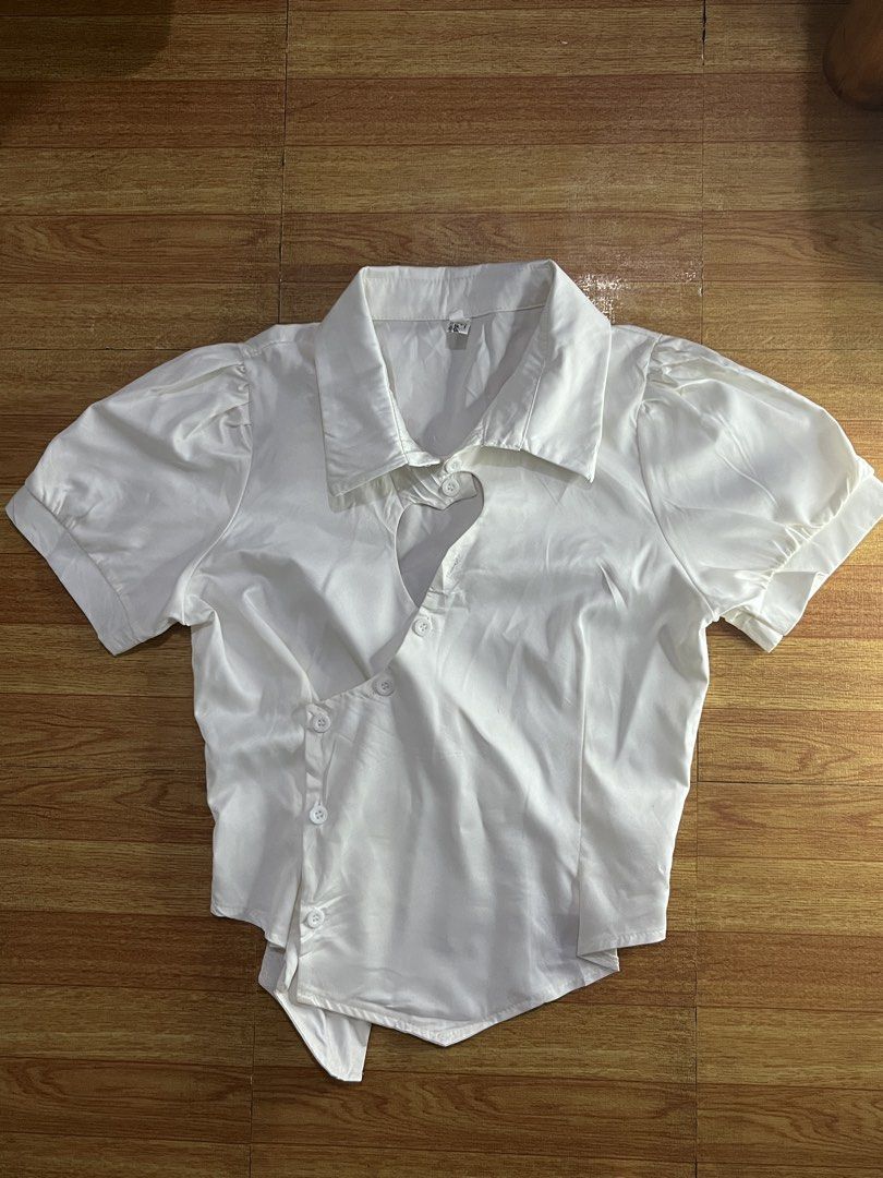 White Asymmetric Button-Down Blouse with Heart Cutout (Category: Blouses) located in Manila. Submitted by lilydmissy (Listing ID 1467611166, Image 1). Description: - Color: White - Design: Short sleeves with puff shoulders, classic collar - Unique Details: Asymmetric diagonal button closure and a sweet heart-shaped cutout below the collar - Fit: Asymmetric hemline that hangs lower on one side - Fabric: Lightweight and breathable, perfect for dail