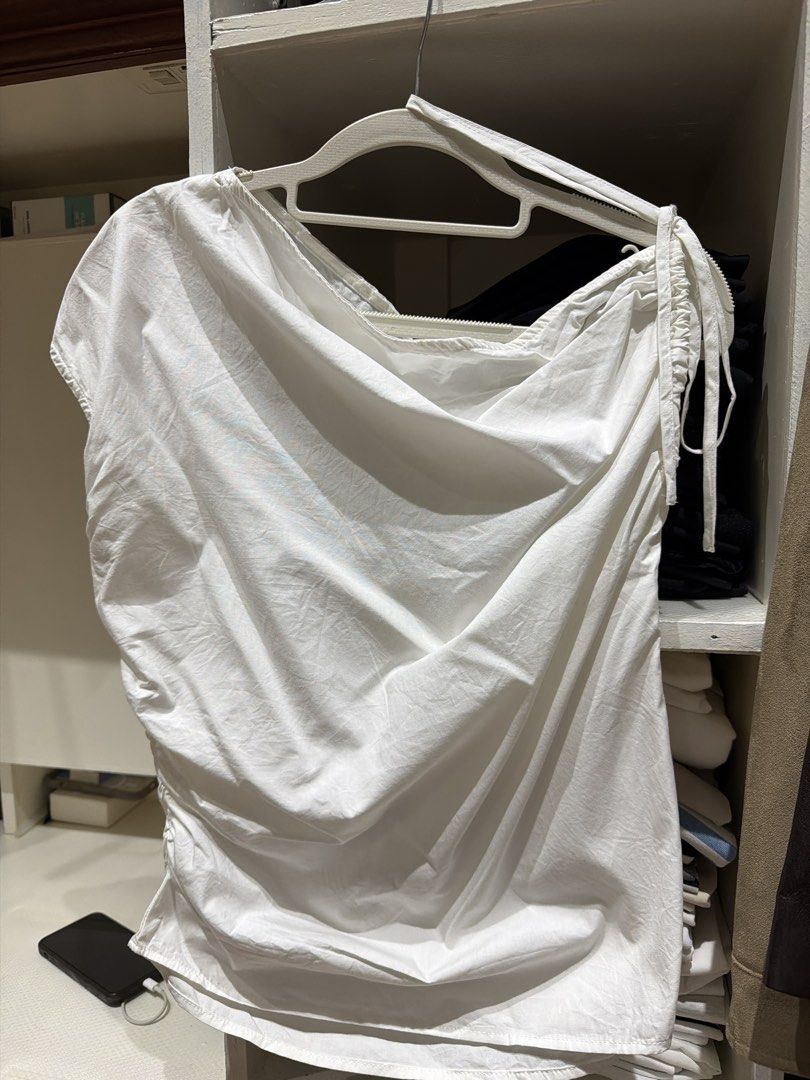 White Asymmetric Drape Top with Ruched Details (Category: Sleeveless) located in Batangas. Submitted by luxuryinmyclowset (Listing ID 1467701578, Image 1). Description: - Color: White - Style: Sleeveless top with draped neckline - Details: Side ruching and adjustable drawstring tie on one shoulder - Material: Soft, lightweight cotton-blend - Versatility: Perfect for casual wear, easy to dress up with a skirt or down with jeans.