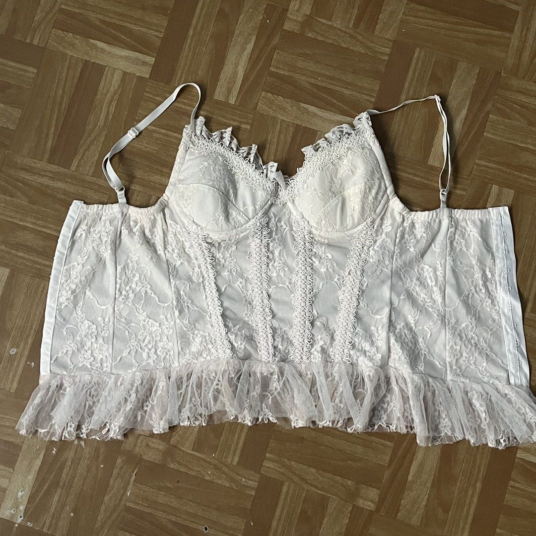 White Lace Corset Top with Ruffle Hem (Category: Sleeveless) located in Santa Rosa. Submitted by peachilee (Listing ID 1467636212, Image 2). Description: - Style: White lace corset top with sheer floral pattern - Details: Structured bustier cups, adjustable shoulder straps, and ruffle mesh trim - Closure: Hook-and-eye closure down the back - Condition: Gentle wear with minor faint discoloration near the bottom hem on the inside lining (unnoticeab