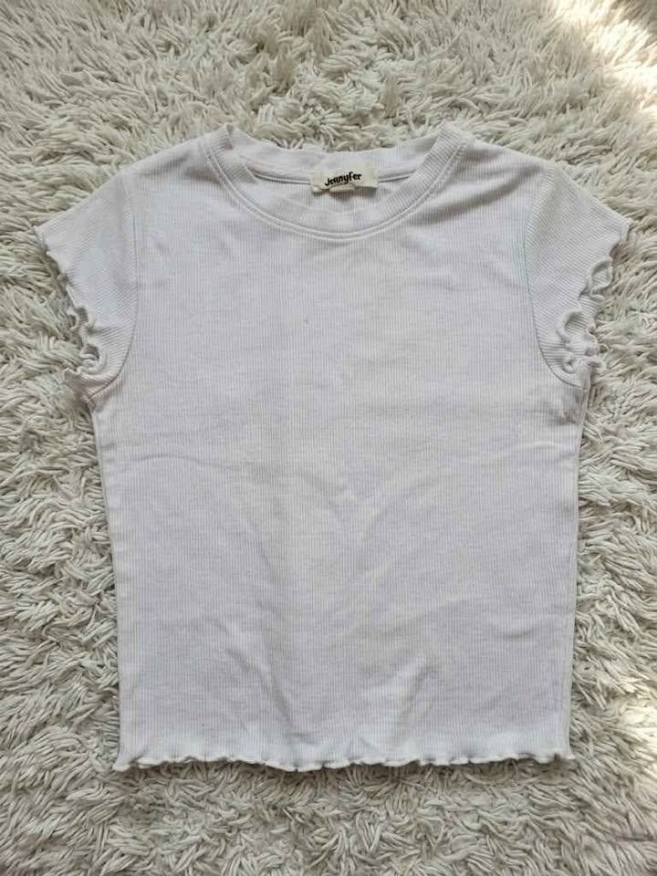 White Ribbed Crop Top (PRELOVED) (Category: Shirts) located in Caloocan City. Submitted by sanyavigor74639 (Listing ID 1467761707, Image 1). Description: - Brand: Jennyfer - Style: White ribbed crop top with crew neck - Details: Short sleeves with trendy lettuce hem edges - Fit: Cropped length, great for pairing with high-waisted jeans or skirts - Material: Soft, textured fabric with slight stretch.