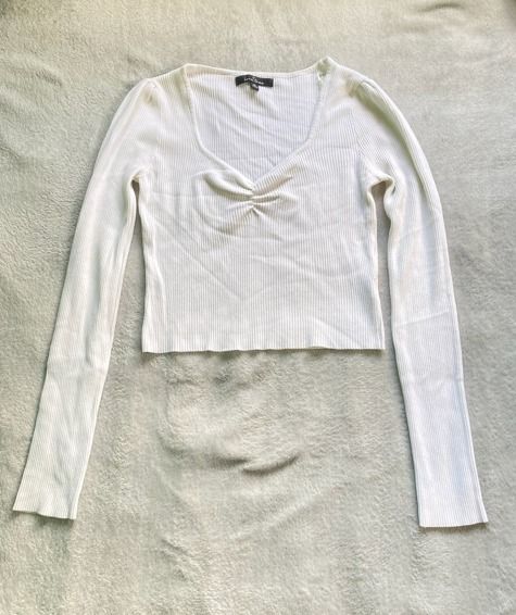 White ribbed long sleeve top with ruched neckline (Category: Longsleeves) located in Rizal. Submitted by sheeraay (Listing ID 1467665686, Image 2). Description: - Color: White - Material: Soft ribbed knit - Fit: Slim fit - Design: Deep V-neckline with front gathered ruched detail - Sleeves: Long sleeves.