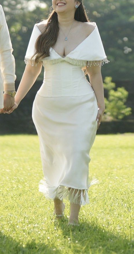 White Satin Pre-wedding Outfit (Category: Evening dresses & gowns) located in Quezon City. Submitted by ericaanderin (Listing ID 1467769595, Image 2). Description: - Color/Material: White satin two-piece set - Style: Structured corset bodice and midi skirt with off-the-shoulder draped sleeves Modern Filipiniana - Details: Delicate fringe tassels along the neckline and hem - Condition: Worn once for a garden photo shoot - Ideal for: Pre-wedding sh