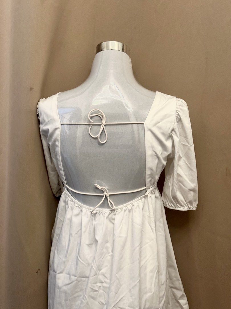 White Square Neck Puff Sleeve Open Back Dress (Category: Dresses) located in Manila. Submitted by jade_preloved19 (Listing ID 1467671012, Image 3). Description: - Color: White - Style: Mini dress with square neckline and gathered puff sleeves - Fit: High waistline with a flattering flared skirt - Back Detail: Open back with two adjustable thin tie straps - Material: Lightweight and breathable cotton - Best For: Casual outings, weekend dates, and 