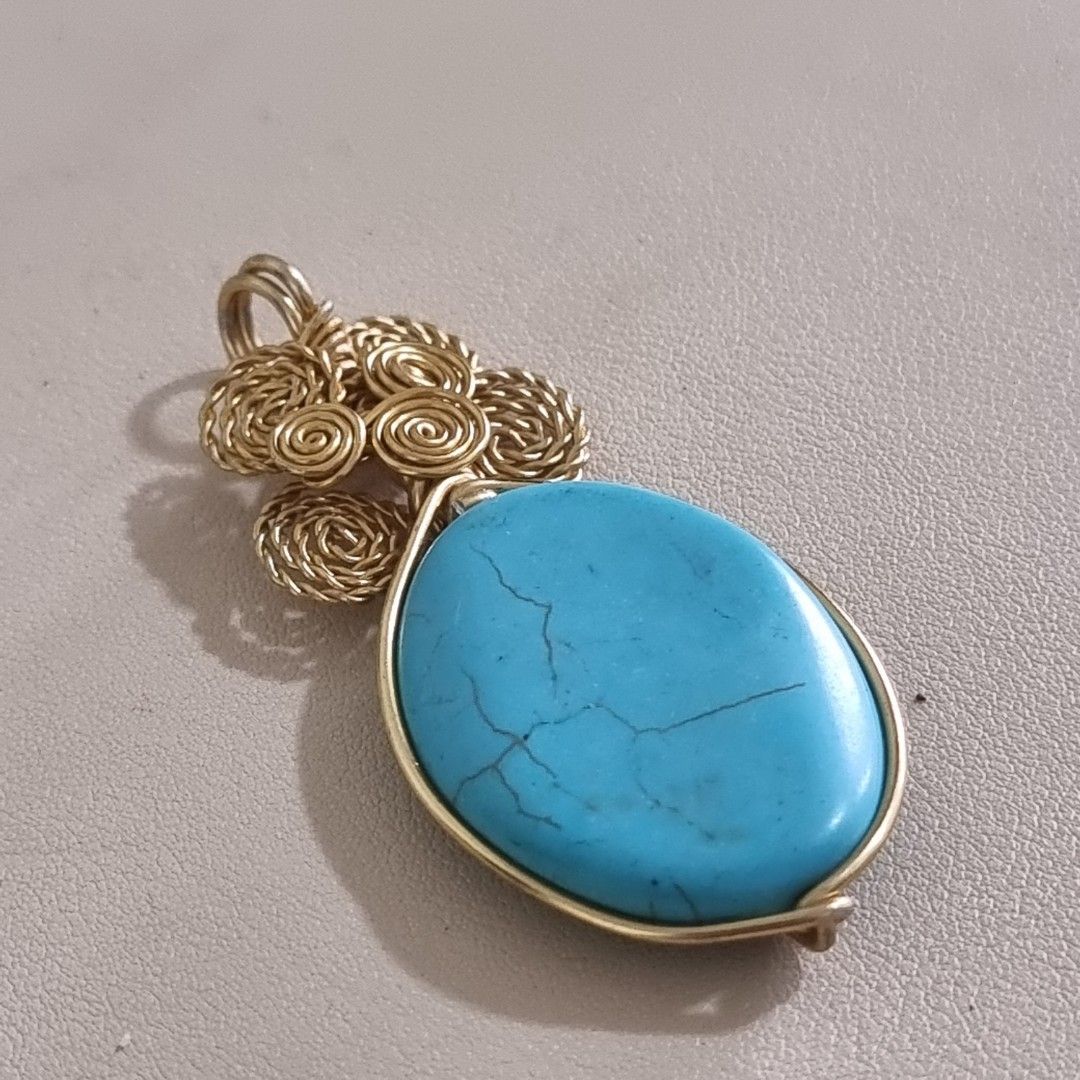 Wire Wrapped Turquoise Oval Pendant (Category: Necklaces) located in Pasig City. Submitted by lesmitch (Listing ID 1467644859, Image 2). Description: - Handmade wire-wrapped pendant with a vibrant blue oval turquoise stone - Intricate gold-toned wire work featuring a charming cluster of spiral roses - Neatly finished artisan detailing on the back frame - Secure top loop ready for any chain or cord - Perfect unique accessory or gift for any occasi