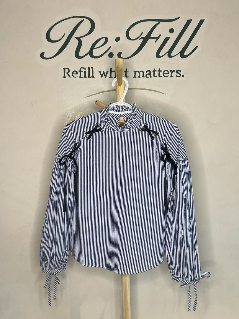 Zara Basic Blue White Striped Blouse Size M (Category: Blouses) located in Taguig. Submitted by re.wear.mnl (Listing ID 1467709584, Image 1). Description: - Brand: Zara Basic - Size: M - Material: 100% cotton - Design: Blue and white vertical stripes with black ribbon lace-up shoulder details - Neckline: High ruffled neck with back keyhole button closure - Sleeves: Long balloon sleeves with tie cuffs - Condition: Excellent pre-loved condition (re