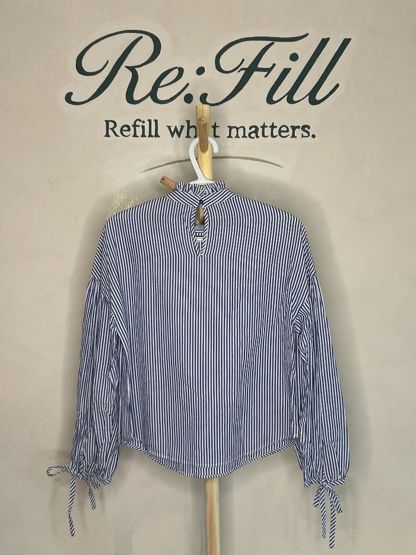 Zara Basic Blue White Striped Blouse Size M (Category: Blouses) located in Taguig. Submitted by re.wear.mnl (Listing ID 1467709584, Image 2). Description: - Brand: Zara Basic - Size: M - Material: 100% cotton - Design: Blue and white vertical stripes with black ribbon lace-up shoulder details - Neckline: High ruffled neck with back keyhole button closure - Sleeves: Long balloon sleeves with tie cuffs - Condition: Excellent pre-loved condition (re