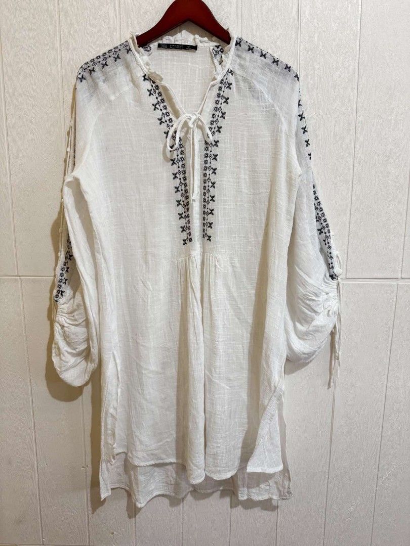 Zara Basic Embroidered White Tunic Blouse Size M (Category: Blouses) located in Calamba. Submitted by iam.hides (Listing ID 1467752781, Image 2). Description: - Brand: Zara Basic - Size: M (Fits true to size) - Color: White with chic black embroidery - Details: Cutout ladder sleeves with drawstrings, tie-neck closure, high-low hem - Material: Lightweight and comfortable - Origin: Made in Morocco - Condition: Excellent / Pre-loved (ready to wear!)