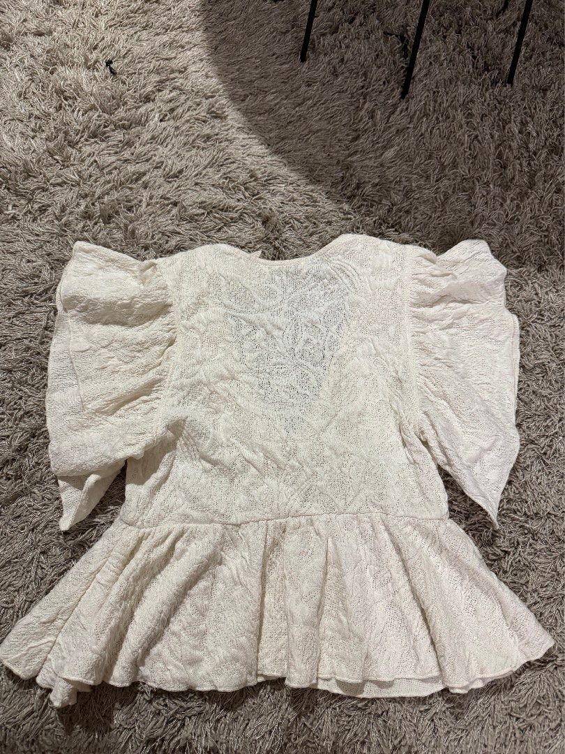 Zara White Textured Ruffle Collar Blouse Size S (Category: Blouses) located in Caloocan City. Submitted by newcrystal_3b43ba (Listing ID 1467739078, Image 3). Description: - Brand: Zara - Size: S - Color: White with textured floral pattern - Details: Short flutter sleeves, large ruffled collar, and peplum hem - Origin: Made in Morocco - Condition: Excellent, clean with no stains or damage.