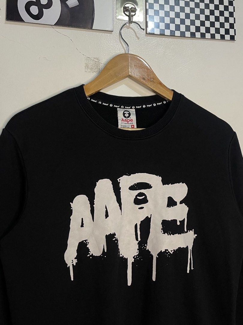 Aape By A Bathing Ape Black Sweatshirt Size M (Category: Coats, Jackets and Outerwear) located in Cabagan. Submitted by blessingma81004 (Listing ID 1467872989, Image 2). Description: - Brand: Aape by A Bathing Ape - Color: Black with big white paint drip logo - Size: Tagged Medium (M) - Material: 100% premium cotton, ribbed cuffs and hem - Details: Signature branding inside collar and back neck DIMENSION: 20 x 25.