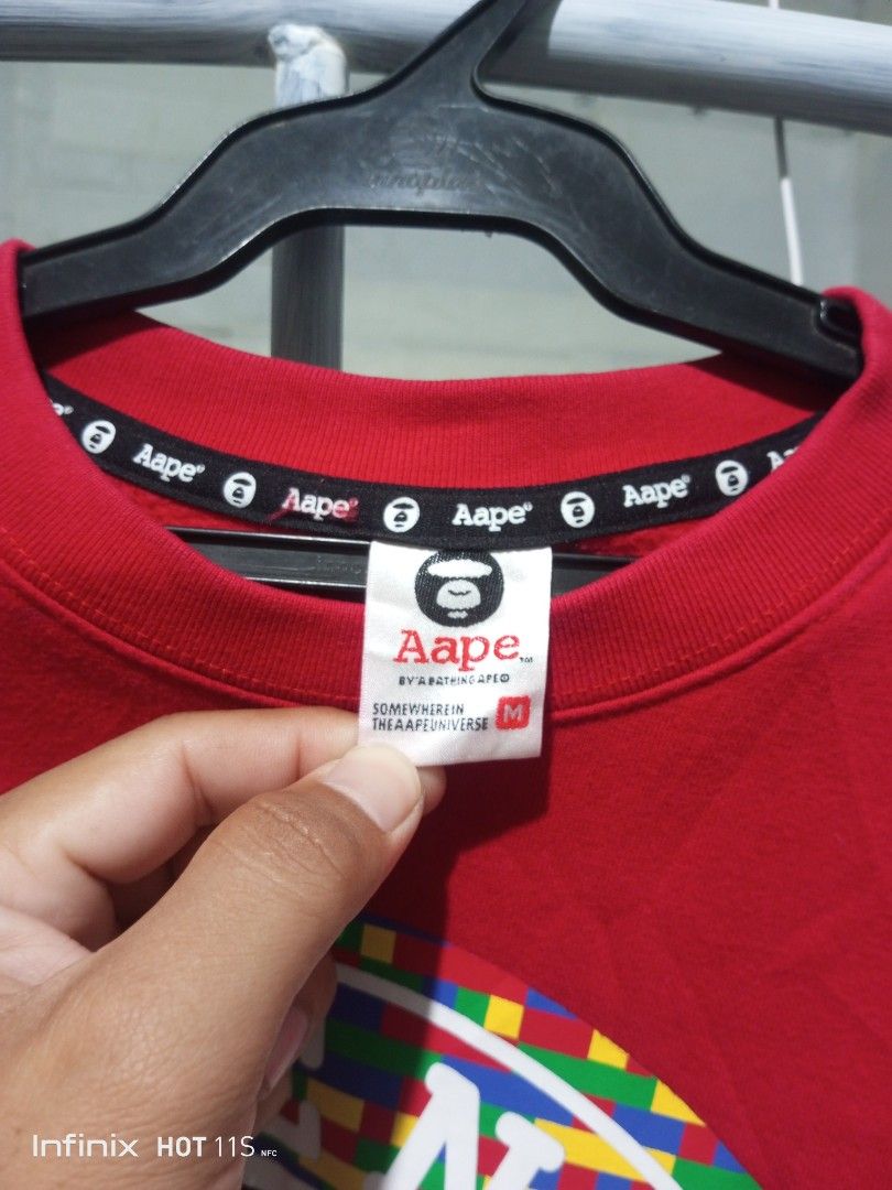 AAPE By A Bathing Ape Red Sweatshirt Size M (Category: Coats, Jackets and Outerwear) located in Las Pinas. Submitted by rzzr_thrift25 (Listing ID 1467939240, Image 3). Description: Red sweatshirt from AAPE by A Bathing Ape. Bold LEGO-style circular logo printed on the chest. Size M tag on the collar. APUNVS text printed on the right sleeve. White embroidered astronaut graphic and branded sleeve tag on the left cuff. Black inner neck tape featurin