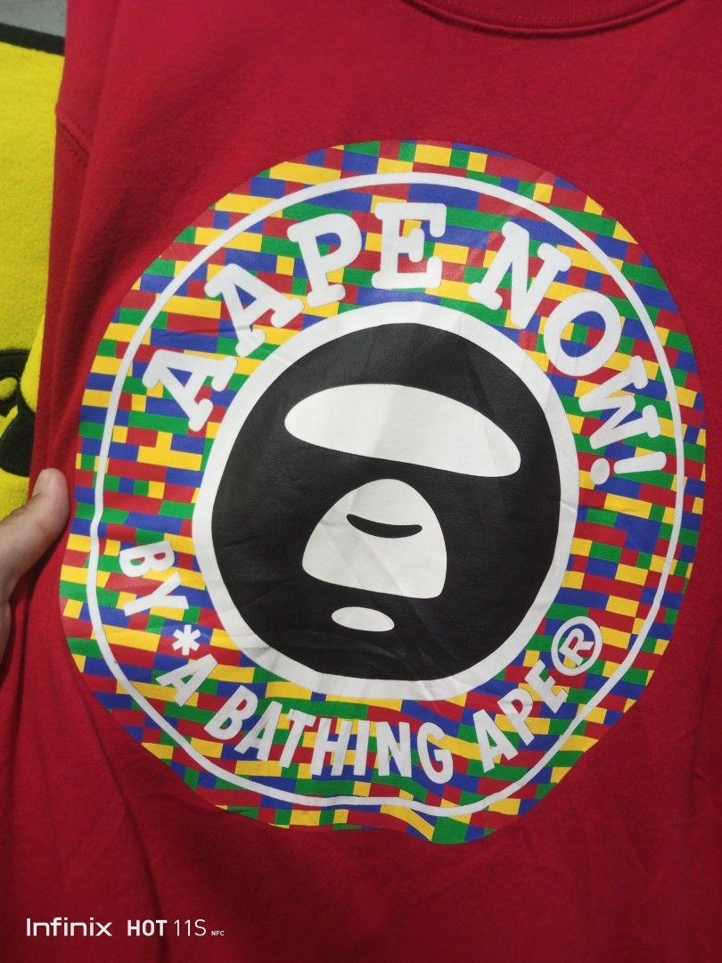 AAPE By A Bathing Ape Red Sweatshirt Size M (Category: Coats, Jackets and Outerwear) located in Las Pinas. Submitted by rzzr_thrift25 (Listing ID 1467939240, Image 2). Description: Red sweatshirt from AAPE by A Bathing Ape. Bold LEGO-style circular logo printed on the chest. Size M tag on the collar. APUNVS text printed on the right sleeve. White embroidered astronaut graphic and branded sleeve tag on the left cuff. Black inner neck tape featurin