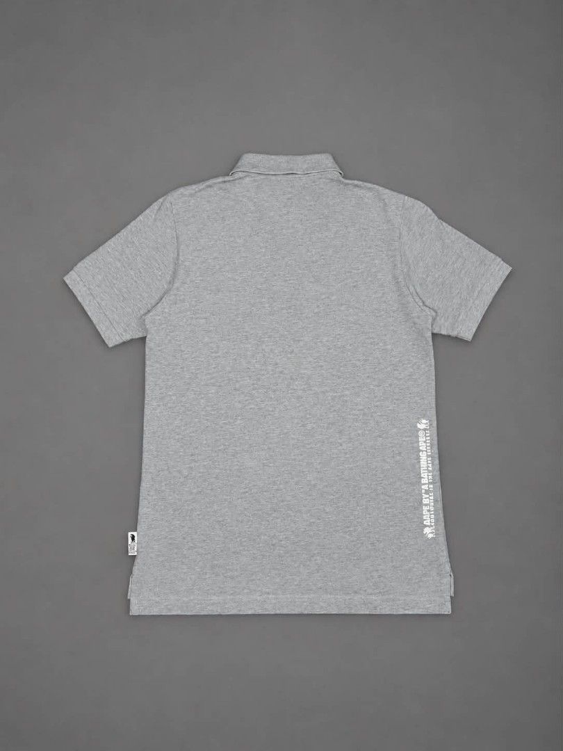 Aape By A Bathing Ape US Flag Patch Polo Shirt (Category: Tshirts & Polo Shirts ) located in Urdaneta. Submitted by jayceegarage (Listing ID 1468026614, Image 2). Description: - Length 25-26 - Width 17.3 - Brand: Aape by A Bathing Ape - Color: Grey - Size: Small - Details: Embroidered American flag ape head patch on chest - Accents: Red, white, and blue patterned fabric lining the button placket - Branding: White text print vertically down the ba