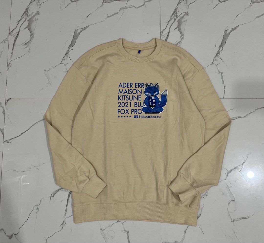 Ader Error x Maison Kitsune Fox Pro Sweatshirt (Category: Coats, Jackets and Outerwear) located in Manila. Submitted by obedmagall74424 (Listing ID 1467876410, Image 1). Description: - Brand: Ader Error x Maison Kitsune (2021 Blue Fox Pro Collection) - Color & Material: Beige, thick premium cotton - Design: Large blue fox chest patch with blue text graphics - Details: Small blue fox logo patch on the back shoulder, blue brand tag inside the neckl