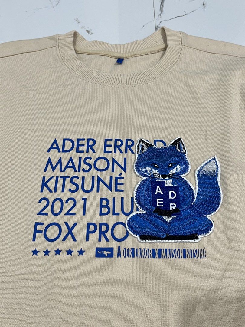 Ader Error x Maison Kitsune Fox Pro Sweatshirt (Category: Coats, Jackets and Outerwear) located in Manila. Submitted by obedmagall74424 (Listing ID 1467876410, Image 3). Description: - Brand: Ader Error x Maison Kitsune (2021 Blue Fox Pro Collection) - Color & Material: Beige, thick premium cotton - Design: Large blue fox chest patch with blue text graphics - Details: Small blue fox logo patch on the back shoulder, blue brand tag inside the neckl