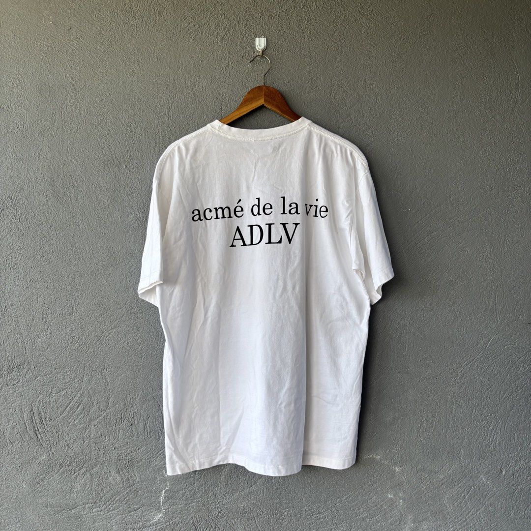 Adlv tee (Category: Formal Shirts) located in San Fernando. Submitted by diff.thr1ft (Listing ID 1467864949, Image 2). Description: - Brand: acmé de la vie (ADLV) - Color: White - Design: Minimalist small logo on the front chest and bold ADLV branding on the back - Material: 100% Cotton, comfortable for everyday wear - Condition: Well-maintained and pre-loved - Perfect for streetwear and casual looks.