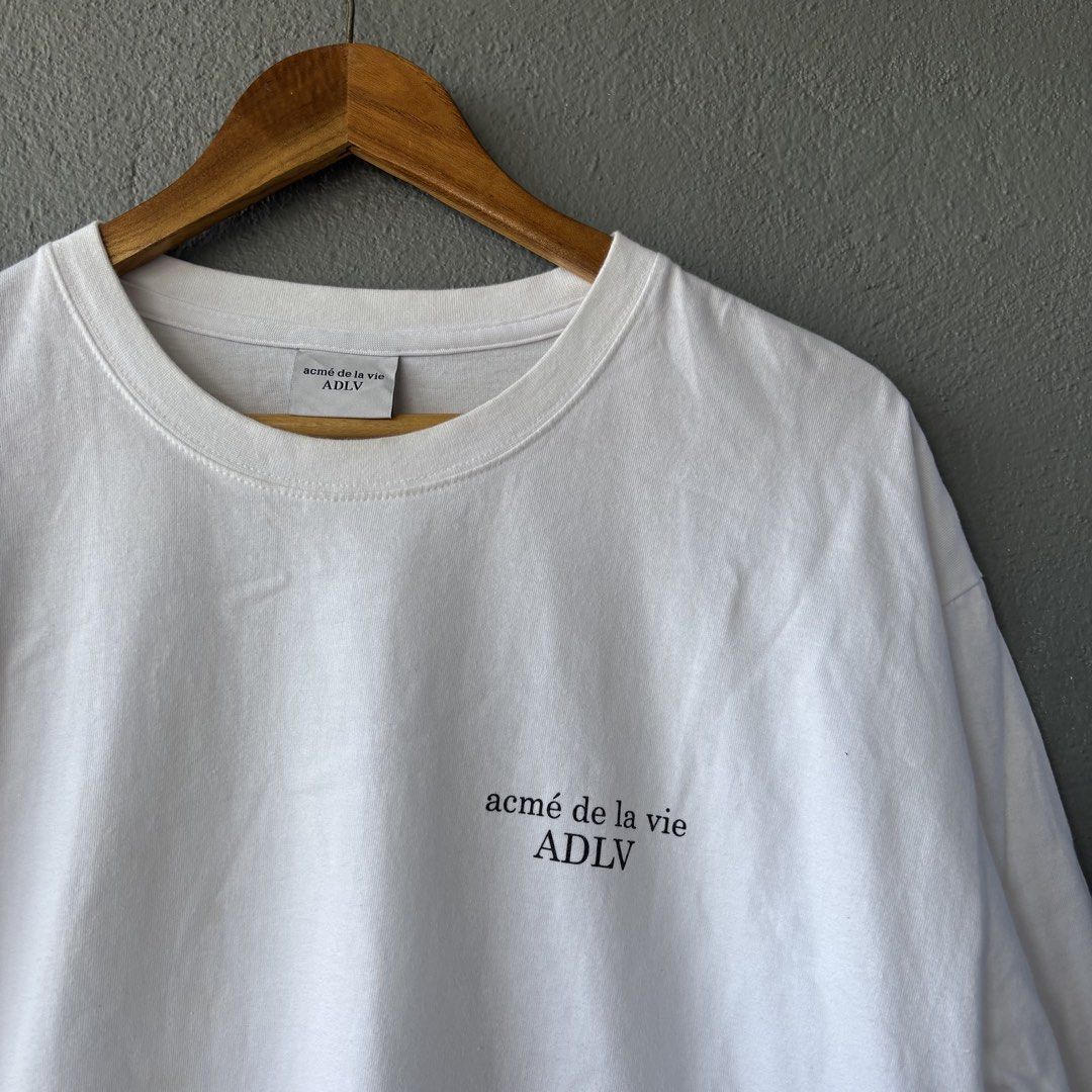 Adlv tee (Category: Formal Shirts) located in San Fernando. Submitted by diff.thr1ft (Listing ID 1467864949, Image 3). Description: - Brand: acmé de la vie (ADLV) - Color: White - Design: Minimalist small logo on the front chest and bold ADLV branding on the back - Material: 100% Cotton, comfortable for everyday wear - Condition: Well-maintained and pre-loved - Perfect for streetwear and casual looks.