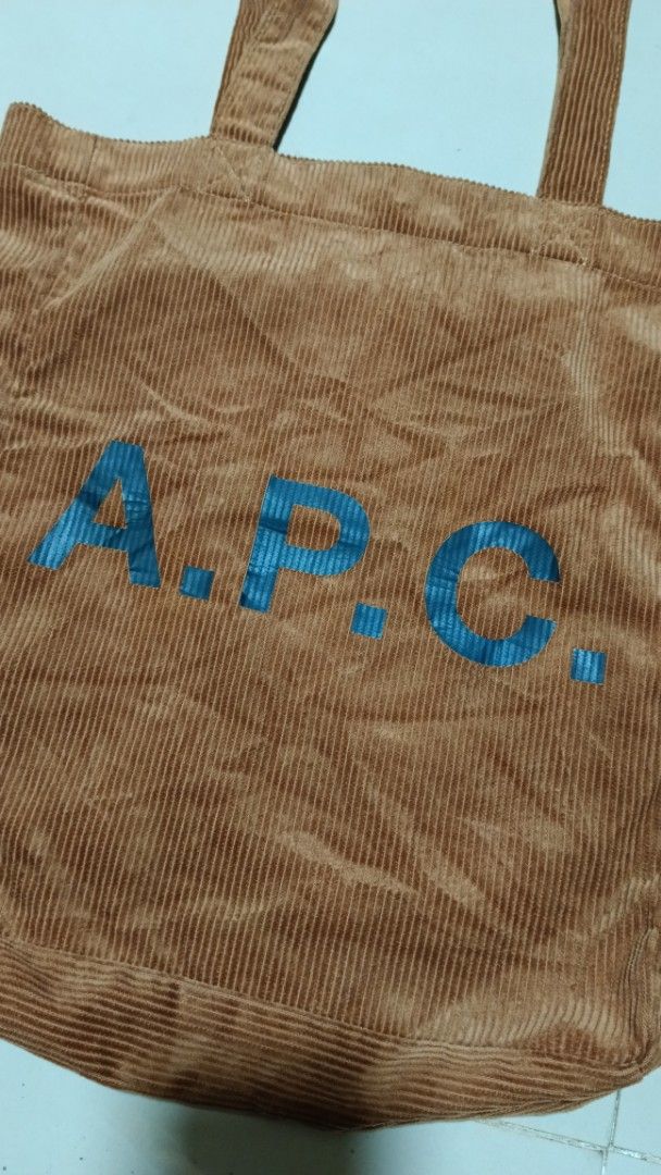 A.P.C. Corduroy Tote Bag (Category: Tote Bags) located in Manila. Submitted by zariyah.1986 (Listing ID 1467964070, Image 2). Description: Brown corduroy tote bag from A.P.C. Rue Madame Paris. Large blue A.P.C. logo stamped on the front. Double shoulder straps with sturdy stitching. Magnetic snap closure at the top opening. Interior slip pockets inside for organization. Soft ribbed fabric texture all over..