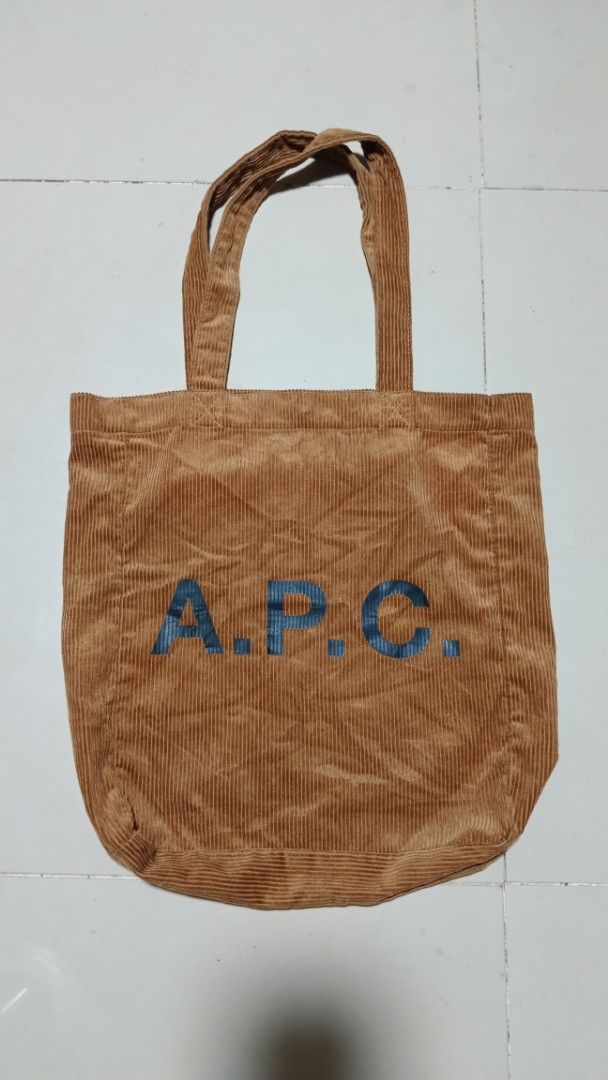 A.P.C. Corduroy Tote Bag (Category: Tote Bags) located in Manila. Submitted by zariyah.1986 (Listing ID 1467964070, Image 1). Description: Brown corduroy tote bag from A.P.C. Rue Madame Paris. Large blue A.P.C. logo stamped on the front. Double shoulder straps with sturdy stitching. Magnetic snap closure at the top opening. Interior slip pockets inside for organization. Soft ribbed fabric texture all over..