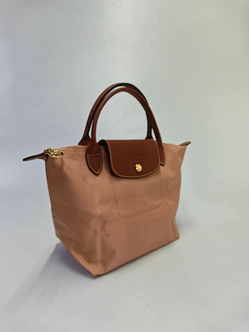 Authentic Longchamp Le Pliage Small Short Handle Top Handle Bag - Pink Tea (Category: Tote Bags) located in Quezon City. Submitted by hollowwillow (Listing ID 1467859083, Image 2). Description: - Authentic Longchamp Le Pliage Top Handle Bag - Color: Charming pink nylon with signature brown leather flap and handles - Hardware: Gold-tone snap closure and zipper - Interior: Clean lining with convenient slip pockets - Features: Iconic foldable design