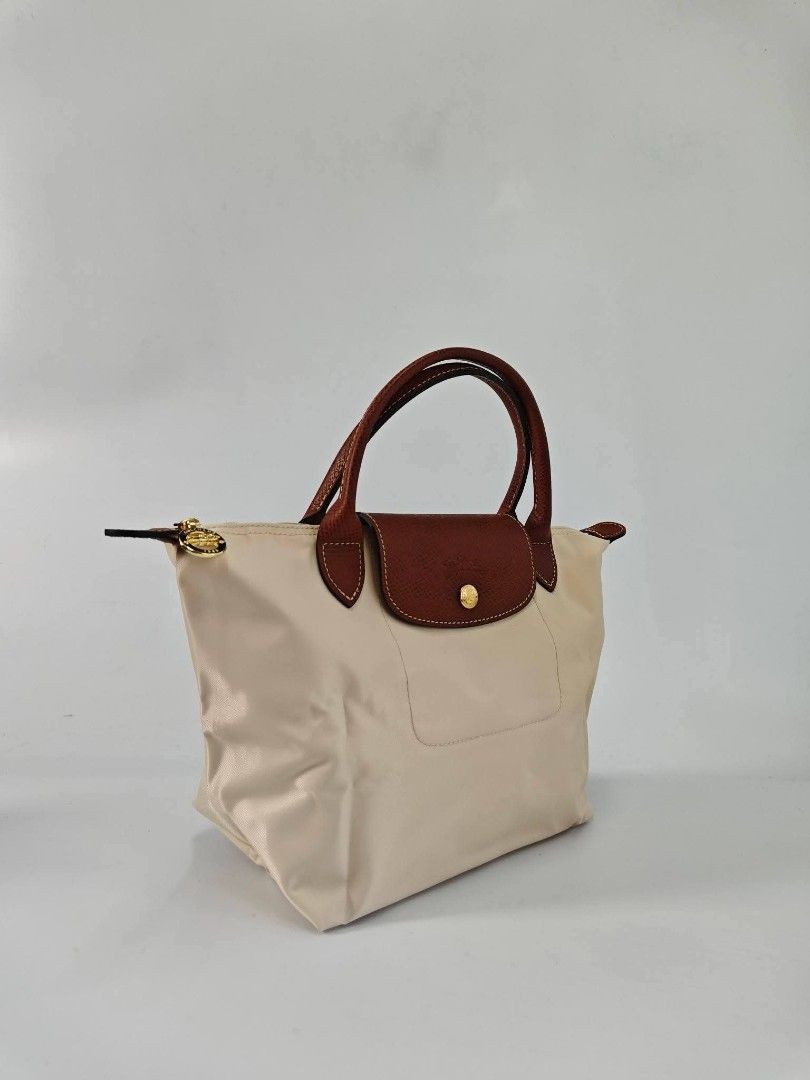 Authentic Longchamp Le Pliage Classic Small Short Handle Handbag - Papier (Category: Purses & Pouches) located in Quezon City. Submitted by hollowwillow (Listing ID 1467991256, Image 2). Description: - Color: papier - Hardware: Polished gold-tone hardware with a secure zipper closure - Interior: Clean cream lining equipped with handy open slip pockets - Design: Structured bottom for stability and a classic top handle style .