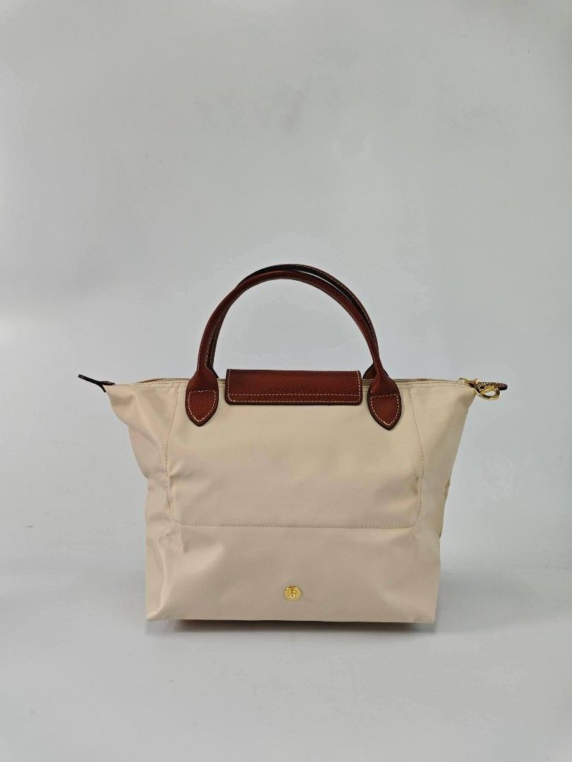 Authentic Longchamp Le Pliage Classic Small Short Handle Handbag - Papier (Category: Purses & Pouches) located in Quezon City. Submitted by hollowwillow (Listing ID 1467991256, Image 3). Description: - Color: papier - Hardware: Polished gold-tone hardware with a secure zipper closure - Interior: Clean cream lining equipped with handy open slip pockets - Design: Structured bottom for stability and a classic top handle style .