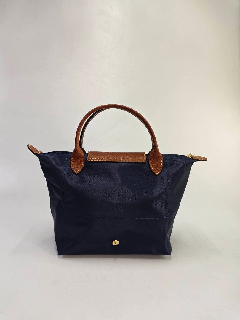 Authentic Longchamp Le Pliage Classic Small Short Handle Handbag - Navy (Category: Purses & Pouches) located in Quezon City. Submitted by hollowwillow (Listing ID 1468014219, Image 3). Description: - Brand/Model: Longchamp Handbag - Color: Classic Navy Blue with Brown Leather Flap and Handles - Hardware: Gold-tone - Closure: Zipper top with snap button flap - Interior: Dark lining with a convenient slip pocket - Style: Short handle design.