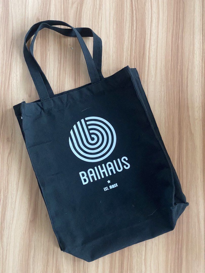 Baihaus Black Canvas Tote Bag (Category: Tote Bags) located in Cebu City. Submitted by bred_bt (Listing ID 1467914781, Image 1). Description: - Brand: Baihaus - Material: Sturdy black canvas - Design: White graphic print with swirl logo and "EST. MMXX" - Features: Secure double shoulder straps - Uses: Ideal for daily errands, school books, or grocery runs - Condition: Brand new.