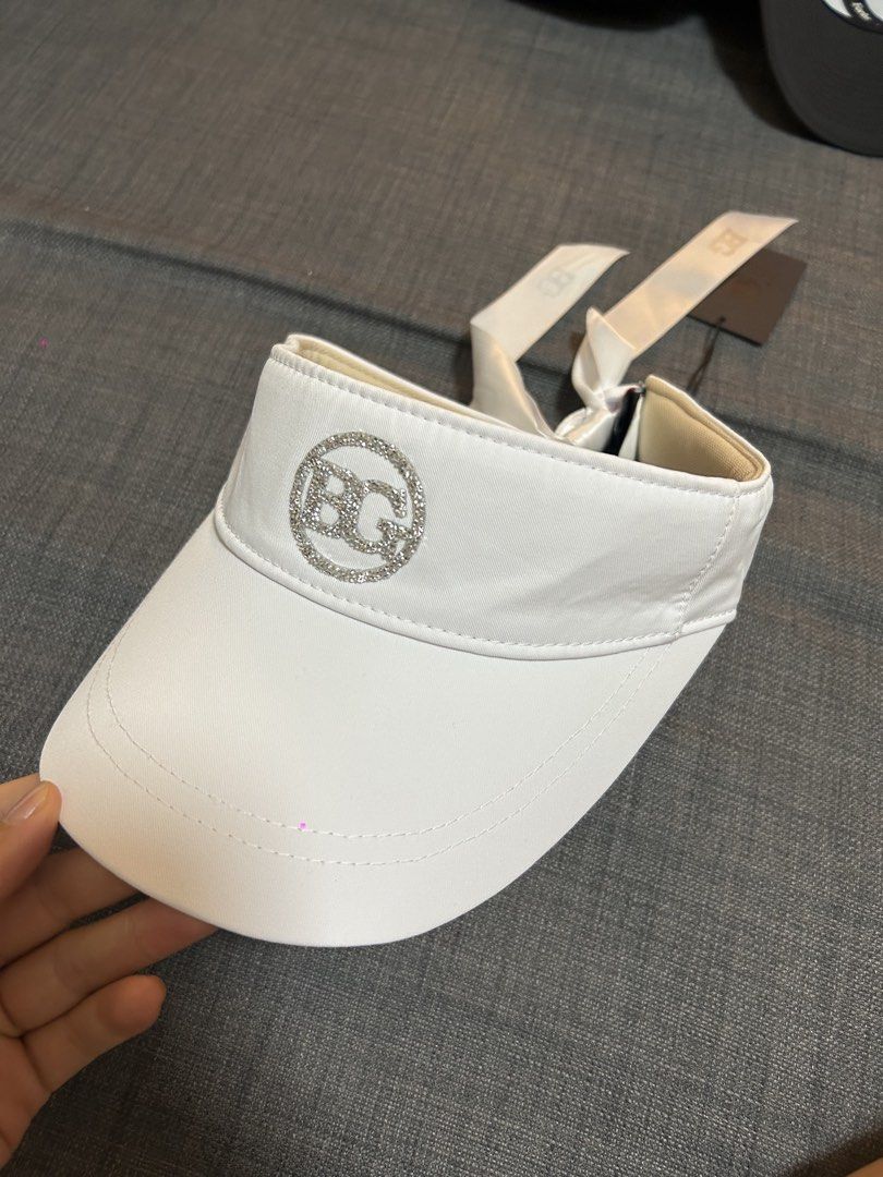 BG Golf Visor White Ribbon Back (Category: Caps & Hats) located in Makati City. Submitted by declutter_forsale (Listing ID 1468014144, Image 2). Description: Originally bought at ₱5600 Reselling for ₱1200 - Brand: BG(BLKTEE GOLF) from Chamule - Color: White - Condition: Brand new with tags, never worn - Features: Sparkly rhinestone logo on the front - Back Detail: Satin ribbon bow with a convenient snap closure - Ideal for: Golf, outdoor sports, 