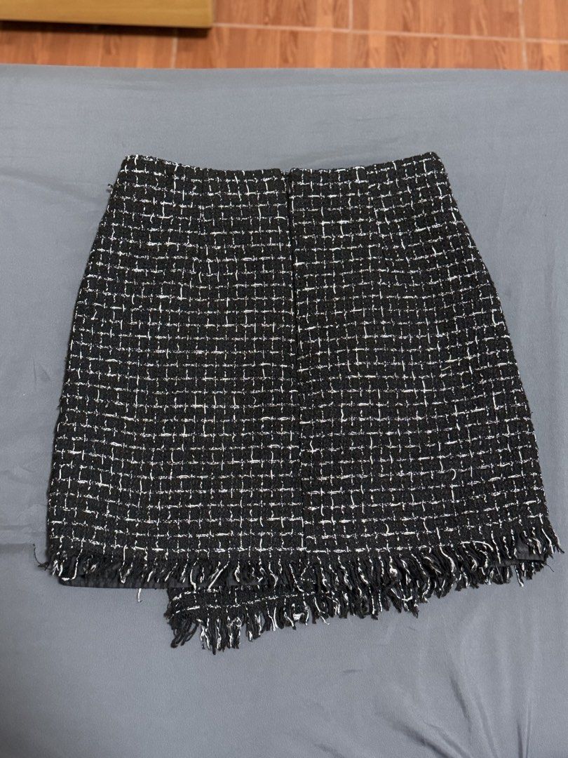 Black and White Tweed Skirt Size M (Category: Skirts) located in Calamba. Submitted by pchyapples (Listing ID 1468028521, Image 2). Description: - Brand: Korean - Made in Italy - Size: M (tag attached) -26-27 waistline - Color/Pattern: Black and white structured plaid tweed with contrast white threading - Style: Wrap-style design with decorative gold-tone ring accents and fringed hem - Interior: Fully lined - Condition: Clean and ready to wear.
