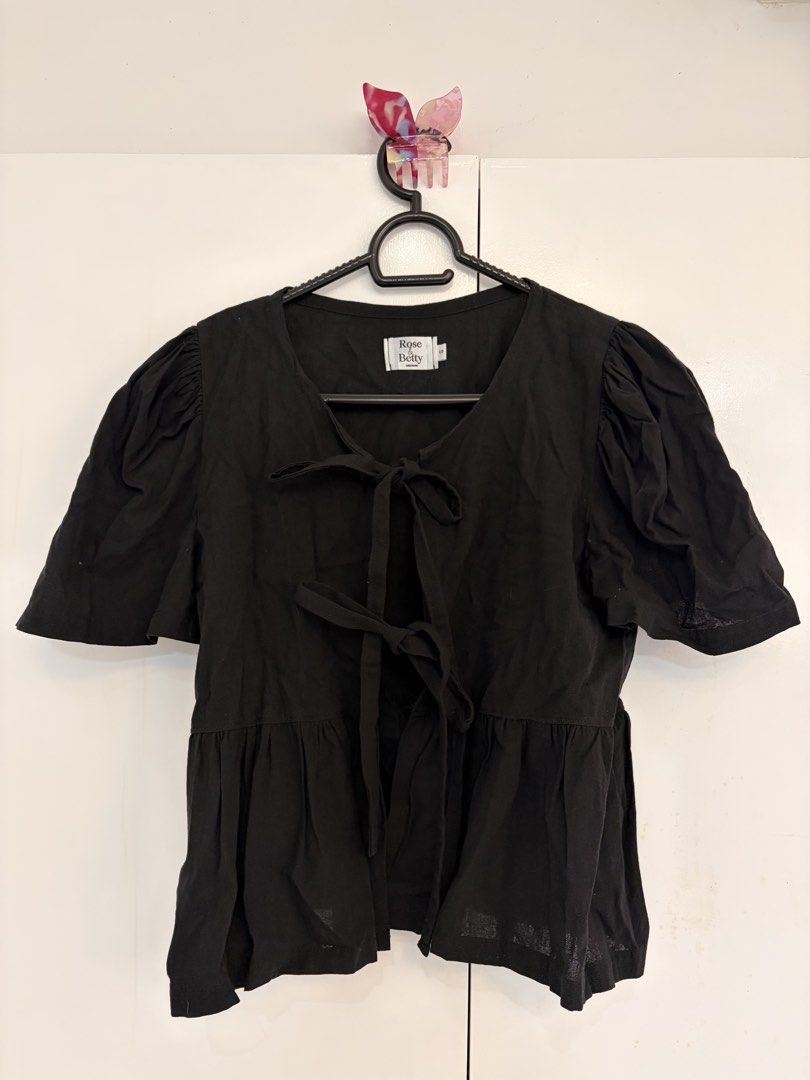 Black Ribbon Tie Blouse (Category: Blouses) located in Quezon City. Submitted by prelovedbynxkole (Listing ID 1467884857, Image 1). Description: - Brand: Rose & Betty Creations - Size: S (tag attached) - Color: Black - Details: Short puffy sleeves, open front with two fabric tie bows, peplum hemline, relaxed fit - Material: Lightweight fabric - Condition: Worn once for a mirror selfie, practically untouched/like new ALL CLOTHES NEED TO BE WASHED 