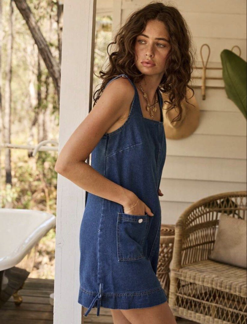 Blue Denim Dress with Pockets (Category: Dresses) located in Quezon City. Submitted by shop_mnl (Listing ID 1467974164, Image 3). Description: - Style: Denim mini dress with a straight silhouette - Neckline & Straps: Square neckline with wide straps - Details: Front utility pockets with metallic snap buttons and side hem ties - Fabric: Medium wash denim with visible contrast stitching - Versatility: Sleeveless design, easy to layer over a tee or 