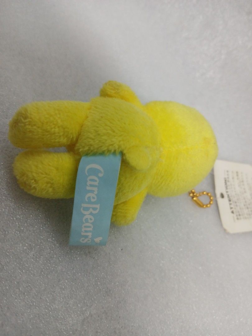 Care Bears Yellow Birthday Bear Plush Keychain (Category: Plushies & Soft Toys) located in Pila. Submitted by Yela.ph_1 (Listing ID 1467947457, Image 3). Description: - Authentic Yellow Care Bears plush keychain - Features a sweet pink cupcake belly symbol with a lit blue candle - Compact size: Measures approximately 6cm tall - Complete with original Japanese hang tag and blue tush tag - Includes a gold ball chain, ready to hang on your bag or ke