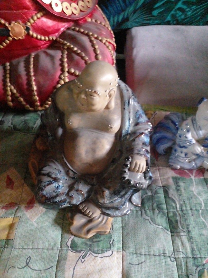 Ceramic Laughing Buddha Figurine with Blue Glaze (Category: Figurines & Statues) located in Quezon City. Submitted by madelrivera (Listing ID 1467997618, Image 2). Description: - Material: Solid ceramic with a sleek dark blue and grey glaze - Design: Laughing Buddha holding prayer beads with detailed facial features and decorative dots - Stability: Sits completely flat on any surface - Placement: Ideal for home altars, bookshelves, or office disp