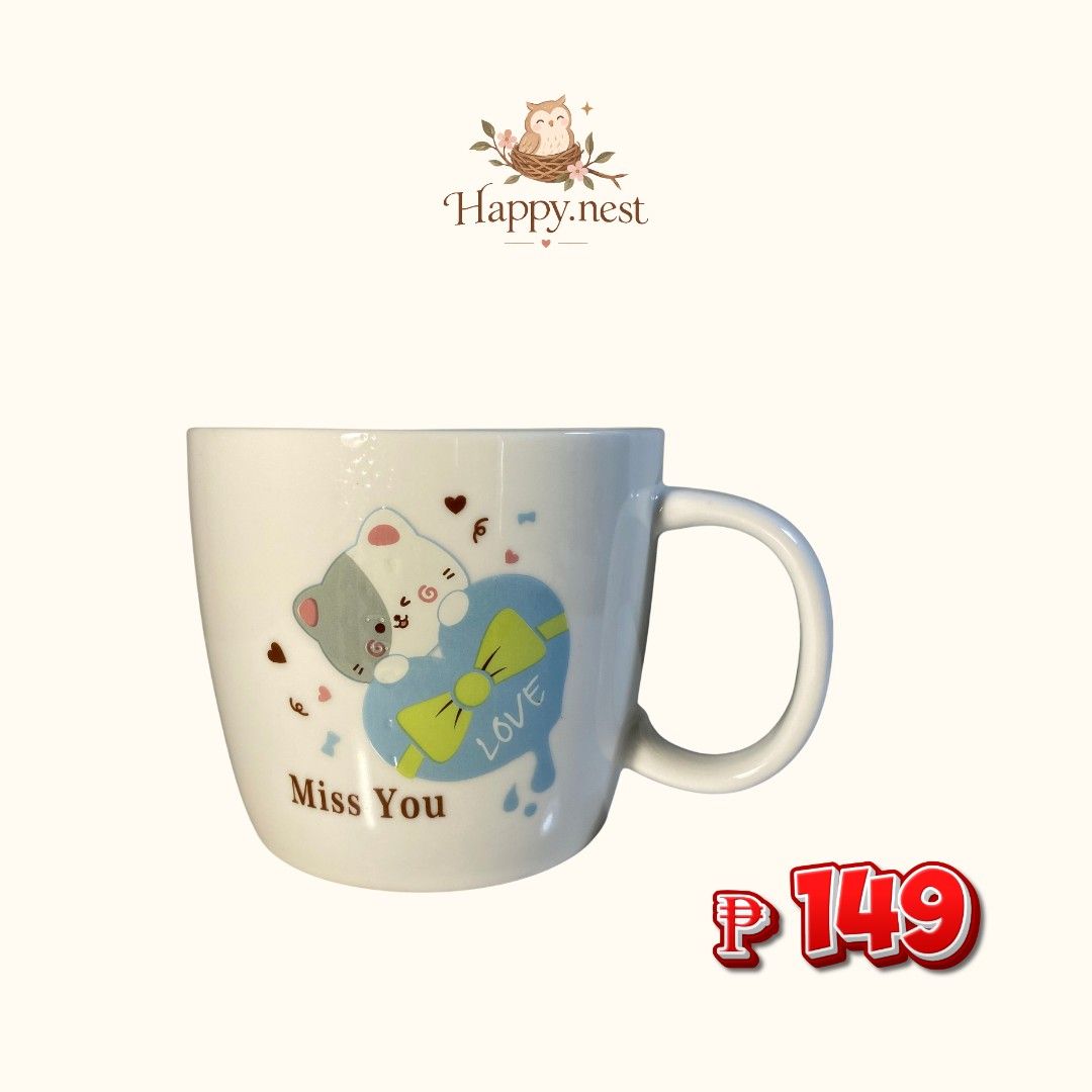 Ceramic Mug (Category: Coffee & Tea Tableware) located in Quezon City. Submitted by oliviararo46032 (Listing ID 1467995738, Image 1). Description: - Brand: Happy.nest - Material: White ceramic with a smooth glazed finish - Design: Cute grey and white cat graphic with a blue heart, green bow, and brown 'Miss You' text - Features: Standard side handle, comfortable grip - Condition: Brand new - Perfect for: Daily coffee, tea, or as a gift for cat lo