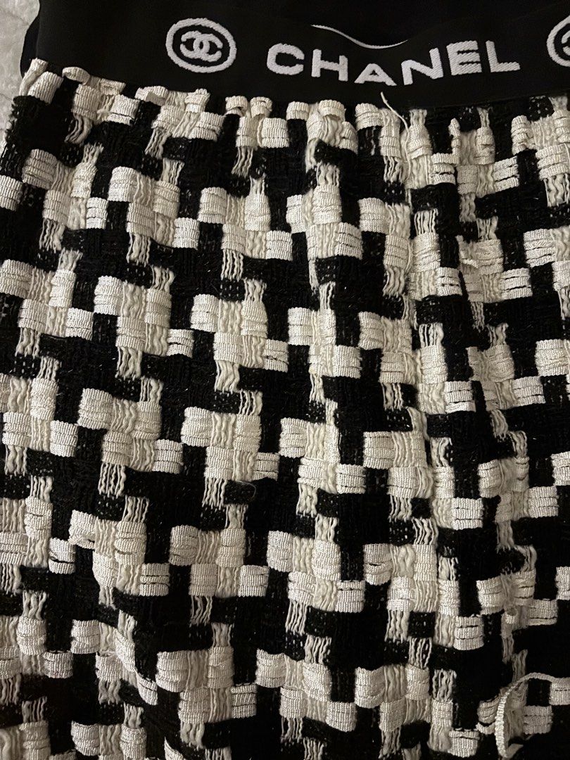 Chanel Black White Houndstooth Tweed Mini Skirt (Category: Skirts) located in Quezon City. Submitted by hadescloset (Listing ID 1468029524, Image 3). Description: - Style: Black and white houndstooth tweed mini skirt - Waistband: Elastic with bold white Chanel lettering and logo branding - Fit: Structured flared cut - Details: Scalloped trim finish along the bottom hem - Styling: Pairs easily with basic black tops and tees.