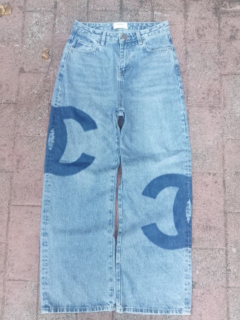 Chanel Denim Jeans with Logo Print (Category: Jeans) located in Munoz. Submitted by rogelioarq16817 (Listing ID 1467975038, Image 1). Description: - Light wash denim jeans with statement CC logo print down the legs - Classic straight leg cut with a comfortable mid-rise fit - Standard button closure, belt loops, and classic 5-pocket styling - Features a stylish brown leather patch on the back waistband - Versatile and perfect for casual everyday w