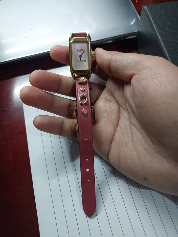 Coach Cadie Watch (Pink Leather Strap) (Category: Women's Watches) located in Caloocan City. Submitted by happydeer_1791cc (Listing ID 1468052695, Image 2). Description: - Brand: Coach - Design: Gold-tone rectangular case with a clean white dial - Strap: Pink leather decorated with floral charms, horseshoe accents, and crystal studs - Inclusions: Comes with original black presentation box - Condition: Excellent, ready to wear -x-x-x- This my most