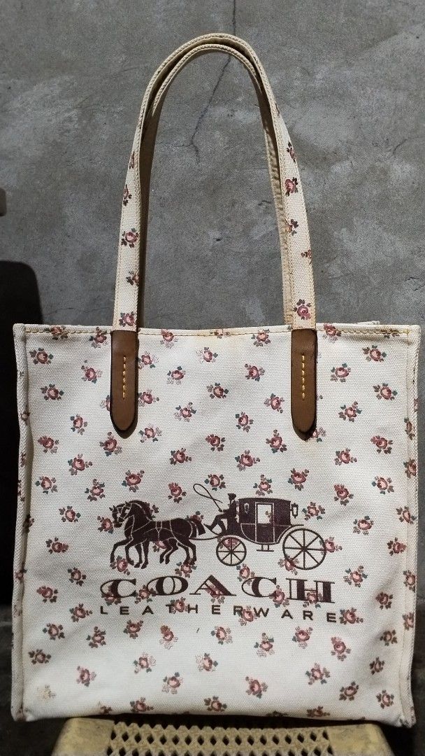 Coach Leatherware Floral Tote Bag (Category: Tote Bags) located in Davao. Submitted by jellisaiah.ocean (Listing ID 1468055035, Image 3). Description: - Brand: Coach - Material: White canvas with brown leather accents - Design: All-over floral pattern with front horse and carriage logo - Features: Spacious main compartment and double leather shoulder straps - Condition: Good, with minor signs of wear near handles and bottom corners - Perfect for 