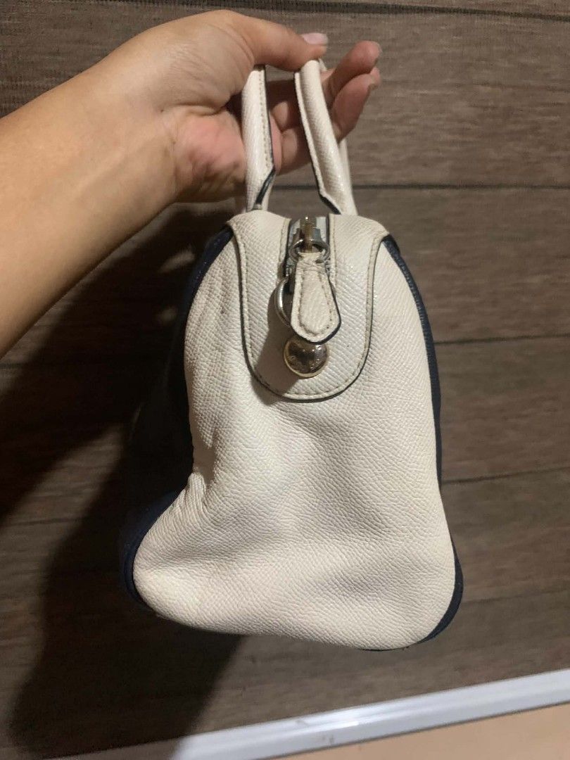 Coach Navy and White Satchel Bag (Category: Luxury Bags & Wallets) located in Aliaga. Submitted by akishaoshop2010. (Listing ID 1468055103, Image 3). Description: - Brand: Coach - Color: Dark navy and white - Material: Premium textured leather - Hardware: Gold-tone with Coach New York logo stamp - Closure: Zip-around - Handles: Dual top handles - Design: Structured shape with protective side panels - Condition: Excellent.