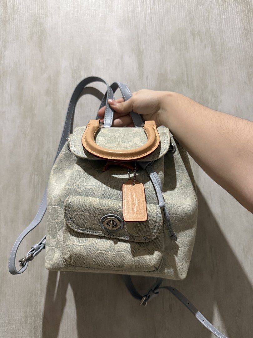 Coach Signature Jacquard Mini backpack with Top Handle (Category: Backpacks) located in Abucay. Submitted by fastlion.584bdf (Listing ID 1468023506, Image 1). Description: Coach mini backpack in light blue and beige signature jacquard fabric. Features a front pocket with a turnlock closure and leather hangtag. Tan leather top handle and adjustable grey straps. Drawstring closure under the main flap. Compact size, handy for daily essentials. Clean