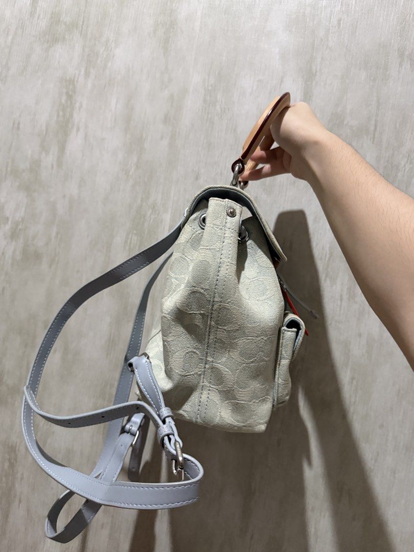 Coach Signature Jacquard Mini backpack with Top Handle (Category: Backpacks) located in Abucay. Submitted by fastlion.584bdf (Listing ID 1468023506, Image 3). Description: Coach mini backpack in light blue and beige signature jacquard fabric. Features a front pocket with a turnlock closure and leather hangtag. Tan leather top handle and adjustable grey straps. Drawstring closure under the main flap. Compact size, handy for daily essentials. Clean