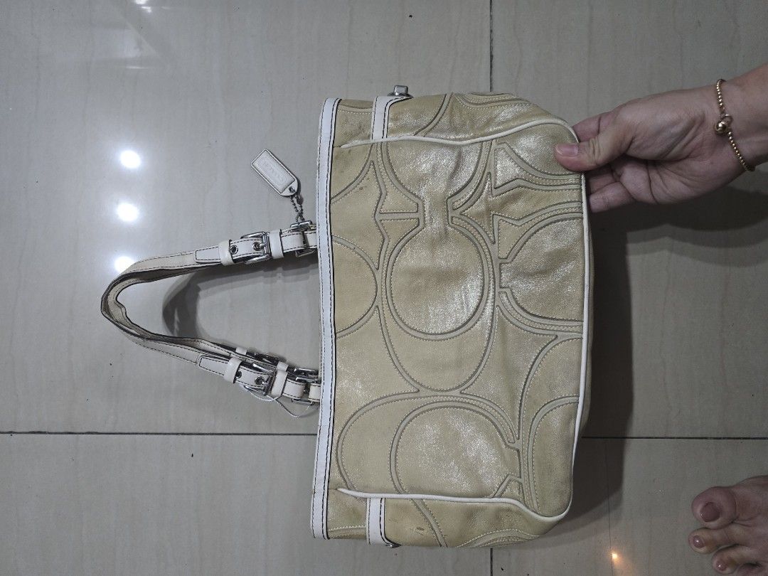 Coach Tote/ Shoulderbag (Category: Luxury Bags & Wallets) located in Manila. Submitted by brandedshoppe_mnl (Listing ID 1467987685, Image 2). Description: - Brand: Coach - Material: Metallic gold leather with white leather trim - Hardware: Silver-tone with protective metal feet on the base - Closure & Straps: Turn-lock side closure with dual buckled shoulder straps - Design: Signature embossed pattern on front and back - Inclusion: Includes match
