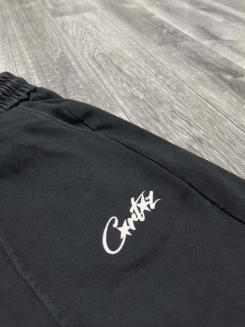 Corteiz Black Sweatshorts HMP (Category: Shorts) located in Manila. Submitted by carloradan59718 (Listing ID 1467872493, Image 3). Description: Black Corteiz sweatshorts with adjustable drawstring waist. White script logo printed near the left front pocket. Back right pocket features a graphic patch with red stars and HMP text. Comfortable thick cotton fleece material. Clean condition overall, minimal wear..