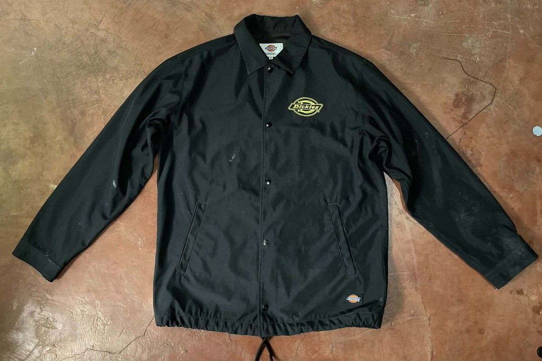 Dickies Black Coaches Jacket Size M (Category: Coats, Jackets and Outerwear) located in Gumaca. Submitted by makuliti (Listing ID 1467955220, Image 1). Description: - Brand: Dickies - Item: Coach Jacket - Color: Black with yellow graphic logo on chest - Size: Medium - Features: Snap-button front, collar, drawstring hem, and side welt pockets - Condition: Shows noticeable scuffs and marks on sleeves and front body as pictured.