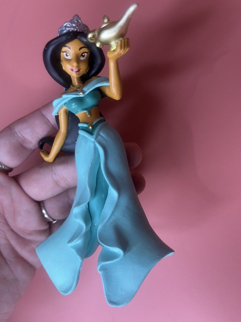 Disney Princess Jasmine Figurine with Magic Lamp (Category: Figurines & Statues) located in Caloocan City. Submitted by snapshop_ph (Listing ID 1468055424, Image 2). Description: - Character: Disney Princess Jasmine holding a gold-colored magic lamp - Appearance: Iconic teal outfit, matching skirt, and tiara in black hair - Authenticity: Official Disney copyright stamp on the underside of the base - Condition: Stands upright on a flat surface; mi