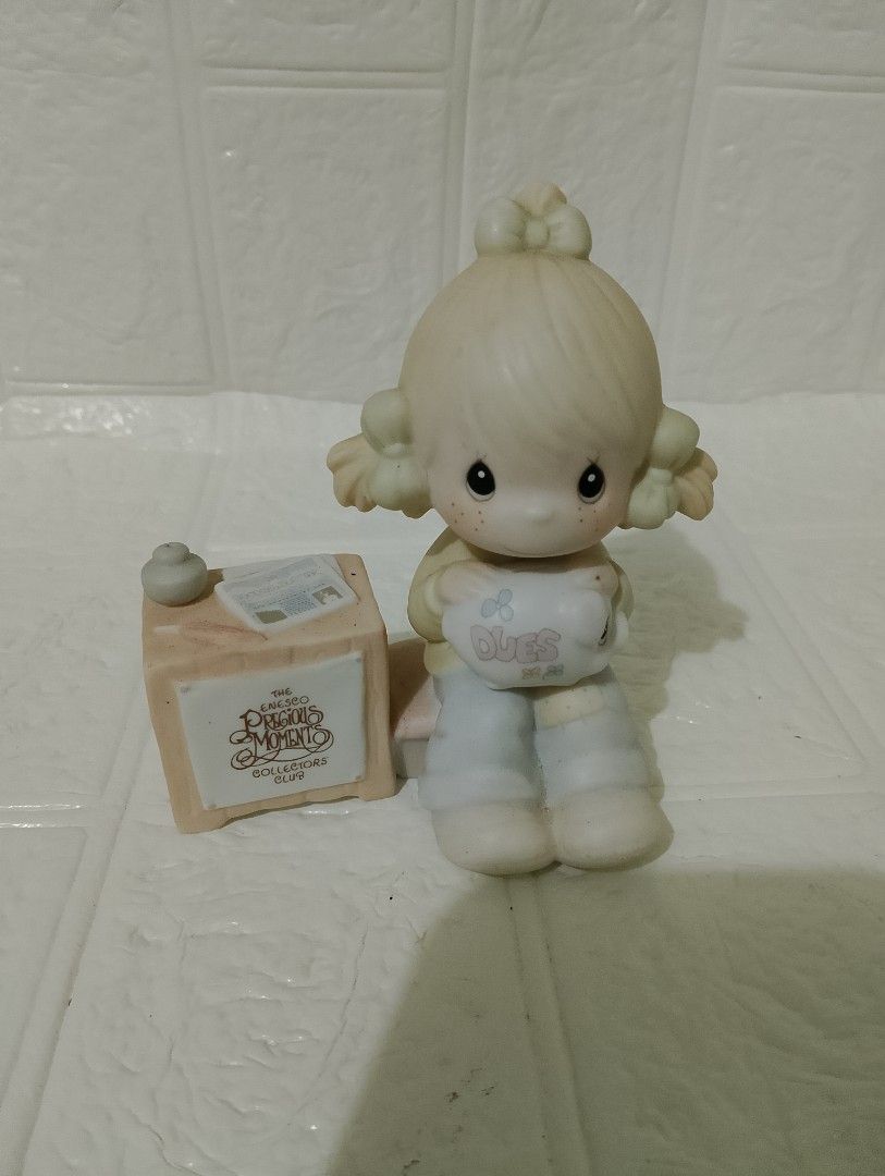 Enesco Precious Moments (Category: Figurines & Statues) located in Manila. Submitted by alygudio (Listing ID 1467849498, Image 1). Description: - Authentic Enesco Precious Moments porcelain figurine - Features a young girl holding a little sheep next to a desk block, newsletter, and inkwell - Official Precious Moments Collectors Club branding on the side - Delicate hand-painted pastel details on hair bows, sweater, and blue pants - Iconic hand-pa