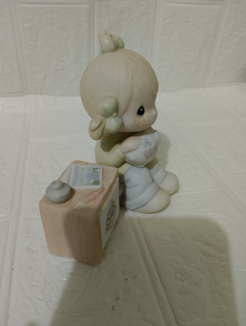 Enesco Precious Moments (Category: Figurines & Statues) located in Manila. Submitted by alygudio (Listing ID 1467849498, Image 2). Description: - Authentic Enesco Precious Moments porcelain figurine - Features a young girl holding a little sheep next to a desk block, newsletter, and inkwell - Official Precious Moments Collectors Club branding on the side - Delicate hand-painted pastel details on hair bows, sweater, and blue pants - Iconic hand-pa