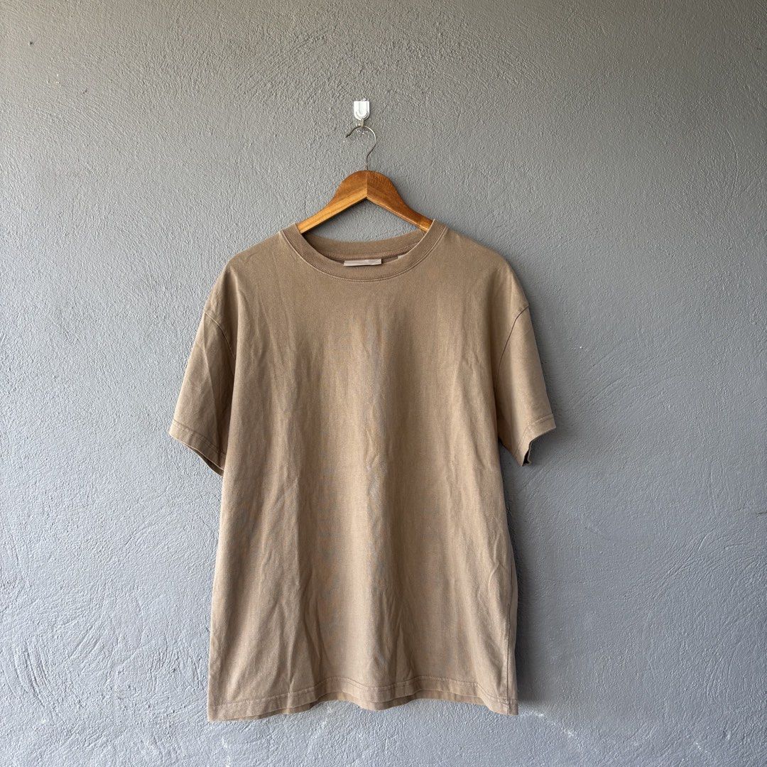 Essential tee shirt (Category: Tshirts & Polo Shirts ) located in San Fernando. Submitted by diff.thr1ft (Listing ID 1467865086, Image 2). Description: - Brand: ESSENTIALS Fear of God - Color: Brown / Earth tone - Size: Medium (M) - Material: 100% cotton, made in Vietnam - Condition: 4/4, well-maintained - Features bold ESSENTIALS Fear of God back lettering and rubberized collar logo patch.